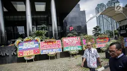 Warga melintas dekat karangan bunga berisi dukungan pada KPK di halaman Gedung KPK, Jakarta, Senin (20/11). Karangan bunga tersebut sebagai bentuk dukungan masyarakat kepada KPK terhadap pemberantasan kasus korupsi e-KTP. (Liputan6.com/Faizal Fanani)