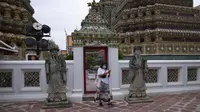 Turis yang mengenakan masker berjalan-jalan di kuil Wat Pho di Bangkok, Thailand, pada 23 Februari 2022. Thailand akan melonggarkan beberapa persyaratan masuk bagi turis asing untuk membangun kembali yang rusak akibat pandemi ekonomi. (AP Photo/Sakchai Lalit)