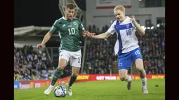 Striker Irlandia Utara, Dion Charles (kiri) berebut bola dengan bek Finlandia, Matti Peltola pada laga kualifikasi Euro 2024 Grup H di Windsor Park, Belfast, Irlandia Utara (27/3/2023). Dion Charles total mencetak dua gol bagi Irlandia Utara dalam dua laga kualifikasi Euro 2024. Dua gol tersebut dilesakkan ke gawang San Marino saat menang 2-0, sementara di laga kedua menghadapi Finlandia ia gagal menyumbang gol saat kalah 0-1. (AP Photo/Peter Morrison)