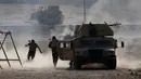 Tentara Irak berlari berlindung dibalik kendaraan militer setelah menembakan RPG saat bertempur melawan ISIS di Al-Qasar, Tenggara Mosul, Irak, (28/11). (REUTERS/Goran Tomasevic)