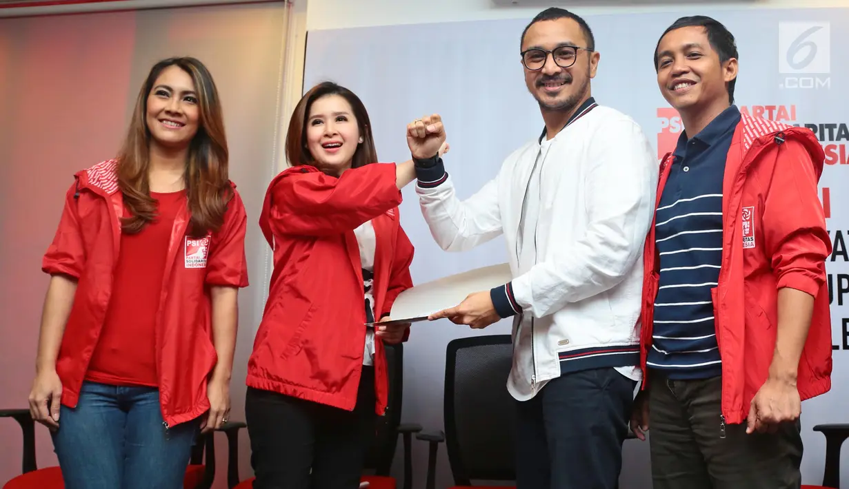Vokalis grup band Nidji, Giring Ganesha dan Ketua Umum Partai Solidaritas Indonesia (PSI) Grace Natalie melakukan slaam komando usai menyerahkan data diri saat mendafar menjadi anggota PSI di Jakarta, Rabu (6/9). (Liputan6.com/Herman Zakharia)