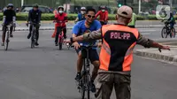 Satpol PP menghentikan pesepeda yang tidak mengenakan masker saat melintas di kawasan Bundaran HI, Jakarta, Minggu (17/1/2021). Pemerintah terus melakukan berbagai upaya guna mencegah penyebaran COVID-19 dan menurunkan angka masyarakat yang terpapar virus corona. (Liputan6.com/Johan Tallo)