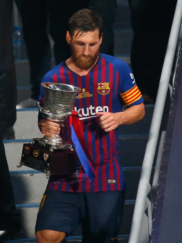 Penyerang Barcelona, Lionel Messi membawa Piala Super Spanyol usai mengalahkan Sevilla di Tangier, Maroko, (13/8). Barcelona meraih gelar ke-13 di Piala Super Spanyol terbanyak ketimbang tim lain. (AP Photo/Mosa'ab Elshamy)