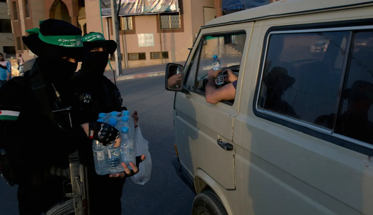 Sejumlah pria bersenjata dan bertopeng Hamas membagikan takjil kepada pengendara mobil jelang berbuka puasa Ramadan di Kota Gaza, Palestina, Kamis (16/5/2019). (AP Photo/Hatem Moussa)