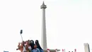 Pengunjung saat berswafoto dengan latar Tugu Monas, Jakarta. (Liputan6.com/Angga Yuniar)