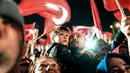 Seorang pria dan anaknya merayakan dan menyambut Presiden Turki Turki Recep Tayyip Erdogan berpidato di dekat markas besar konservatif Partai Keadilan dan Pembangunan (AKP) di Istanbul, Turki (16/4). (AFP Photo / Bulent Kilic)