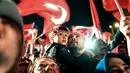 Seorang pria dan anaknya merayakan dan menyambut Presiden Turki Turki Recep Tayyip Erdogan berpidato di dekat markas besar konservatif Partai Keadilan dan Pembangunan (AKP) di Istanbul, Turki (16/4). (AFP Photo / Bulent Kilic)