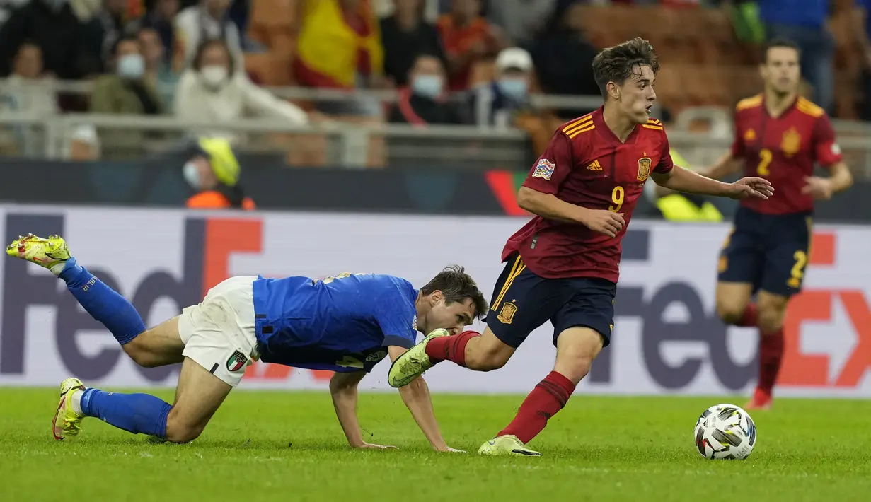 Penyerang Italia Federico Chiesa dan gelandang Spanyol Gavi berebut bola pada pertandingan semifinal UEFA Nations League di stadion San Siro, Rabu (6//9/2021). Wonderkid Barcelona, Gavi mencatatkan sejarah sebagai pemain termuda yang pernah tampil bersama timnas senior Spanyol. (AP/Antonio Calanni)
