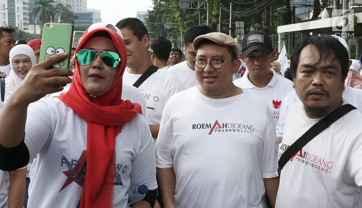 Wakil Ketua Umum Partai Gerindra, Fadli Zon (tengah) berswafoto dengan peserta kegiatan jalan sehat di kawasan Jakarta Pusat, Sabtu (2/2). Acara jalan sehat ini digelar oleh relawan Roemah Djoeang Prabowo-Sandiaga. (Liputan6.com/Herman Zakharia)