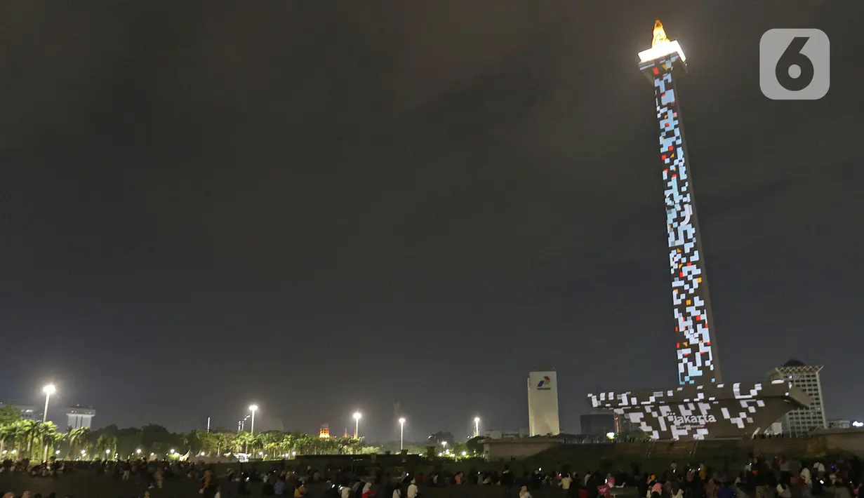 Suasana saat warga menyaksikan pertunjukan video mapping di Monumen Nasional (Monas), Jakarta, Minggu (22/12/2019). Acara ini berlangsung di pelataran barat Tugu Monas pada 22-31 Desember 2019. (Liputan6.com/Herman Zakharia)