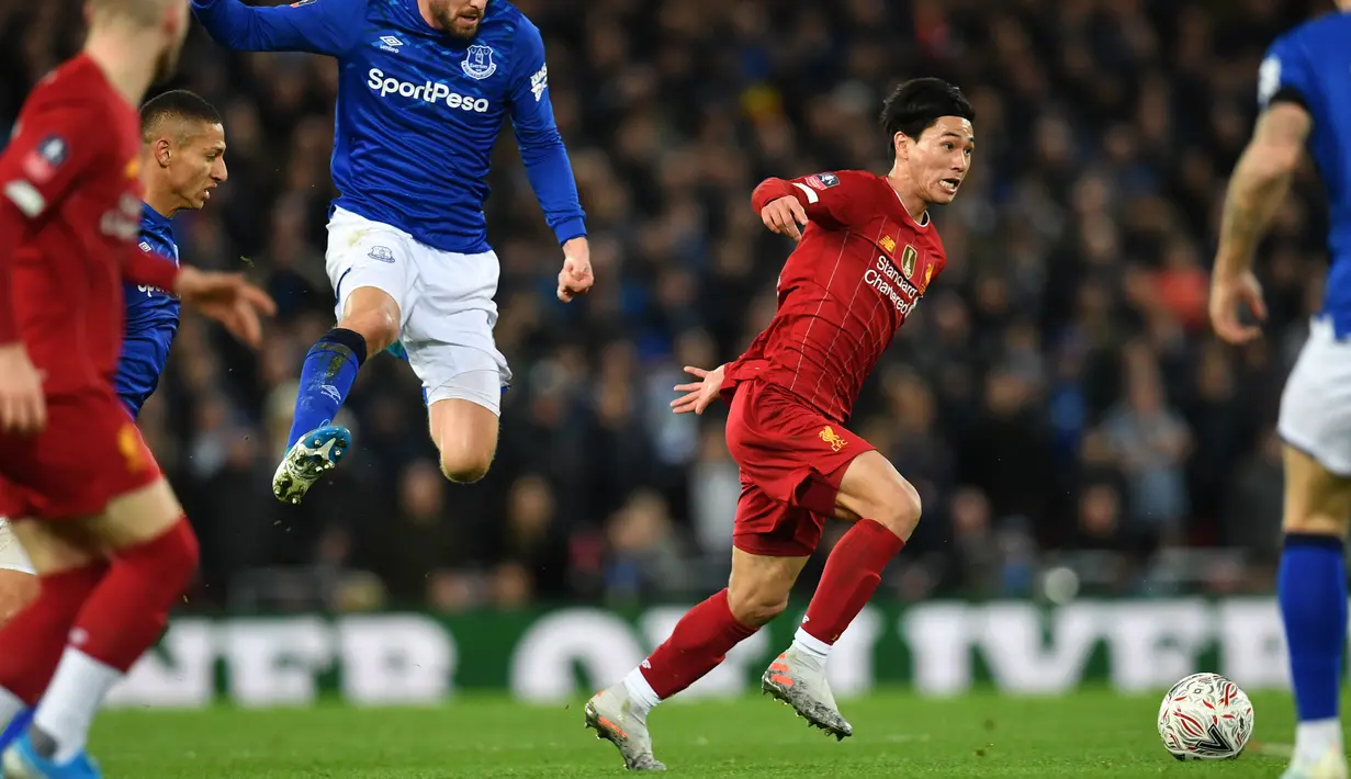Gelandang Liverpool, Takumi Minamino menggiring bola dari kawalan para pemain Everton pada pertandingan babak ketiga Piala FA di Anfield, Minggu (5/1/2020). Pemain Jepang menjalani debut bersama Liverpool dengan menjadi starter dipertandingan tersebut. (AFP/Paul Ellis)