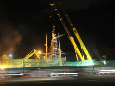 Pekerja menggunakan alat berat melakukan persiapan pemindahan Patung Proklamator Soekarno-Hatta di Jalan Raya Bandara Soekarno-Hatta, Tangerang, Kamis (7/1). Patung ini akan dipindahkan ke bundaran Kawasan Bandara Soetta. (Liputan6.com/Faisal R Syam)