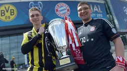 Dua orang suporter Borussia Dortmund dan Bayern Muencehen memegang replika tropi Liga Champions