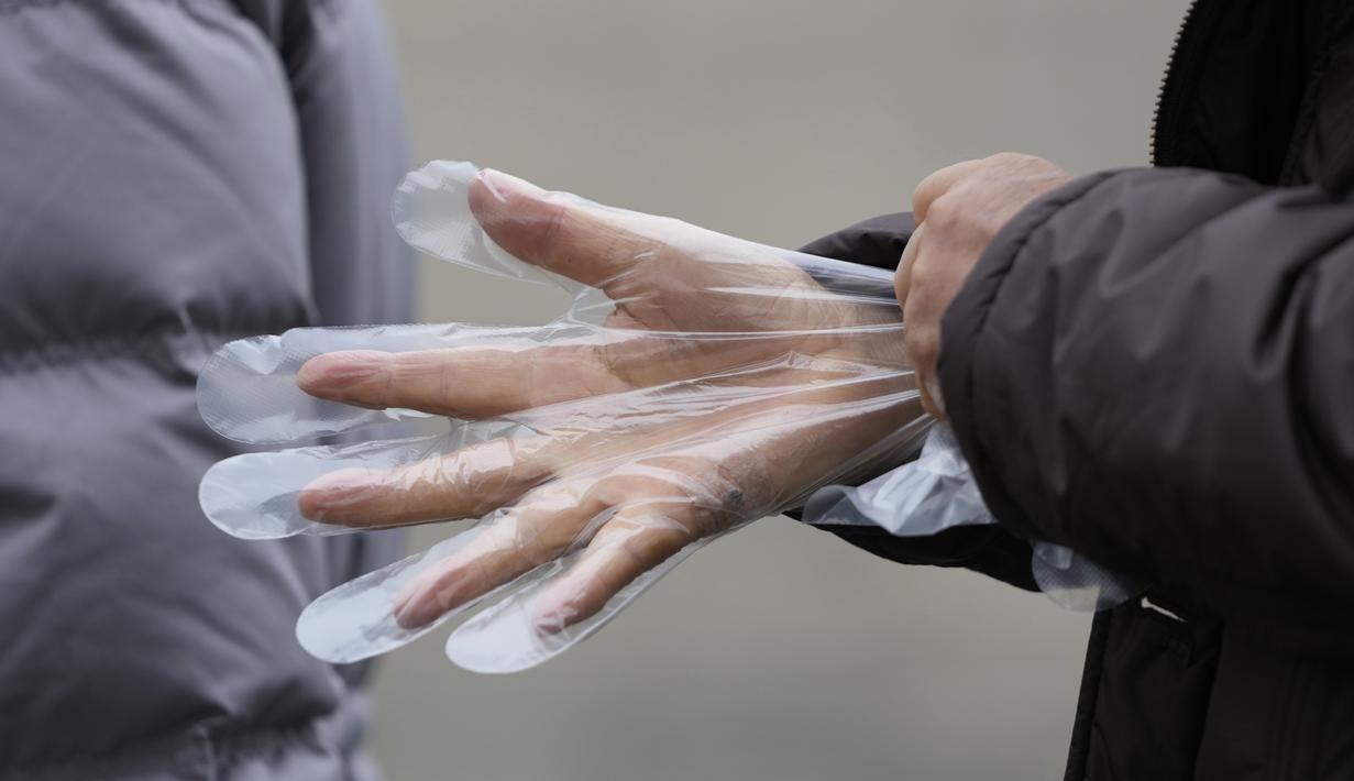 Pengunjung memakai sarung tangan plastik saat antre untuk tes corona di klinik skrining sementara di Seoul, Korea Selatan, Jumat (10/12/2021). Otoritas kesehatan Korea Selatan melaporkan lebih dari 7.000 kasus COVID-19 baru untuk ketiga hari berturut-turut pada hari Jumat ini. (AP Photo/Lee Jin-man)