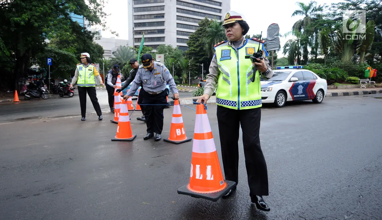 Petugas gabungan memasang tanda saat pengalihan arus di Jalan Jenderal Sudirman, Jakarta, Minggu (31/12). Pengalihan terkait malam puncak perayaan pergantian tahun di kawasan Bundaran HI hingga Jalan MH Thamrin. (Liputan6.com/Helmi Fithriansyah)