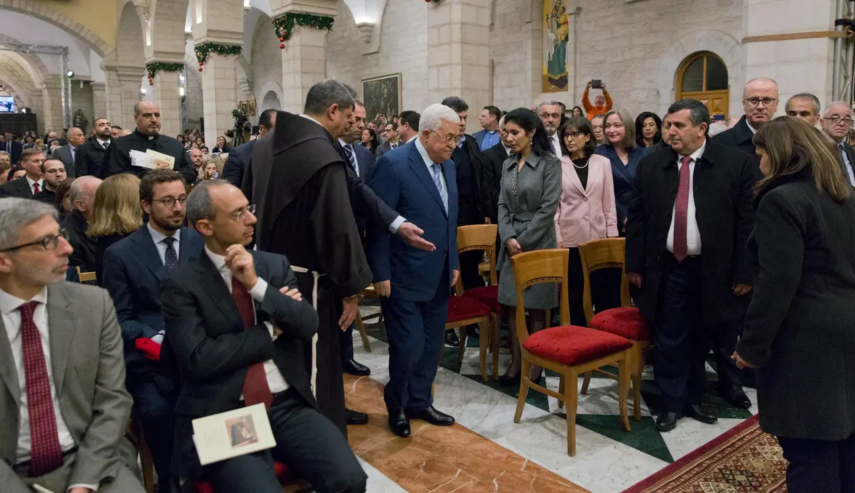 Presiden Palestina Mahmoud Abbas (tengah) tiba untuk menghadiri Misa Malam Natal di Gereja Saint Catherine di kota Betlehem Tepi Barat (25/12). (AFP Photo/Nasser)