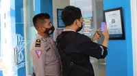 Pemohon SIM ketika menscan barcode aplikasi Peduli Lindungi di pintu keluar masuk Satpas Polres Blora. (Liputan6.com/Ahmad Adirin)