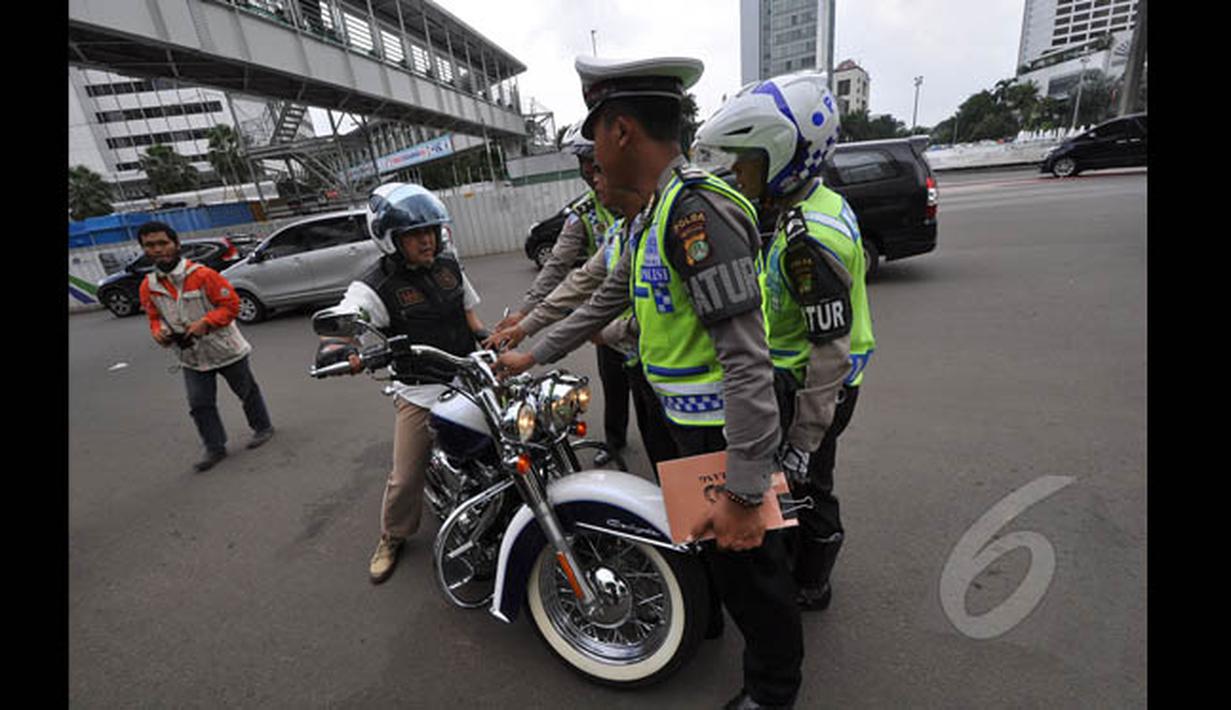 Aparat kepolisian lalu lintas saat memberhentikan pengendara motor gede yang menerobos Jalan MH Thamrin, Jakarta, Minggu (18/1/2015). (Liputan6.com/Miftahul Hayat)