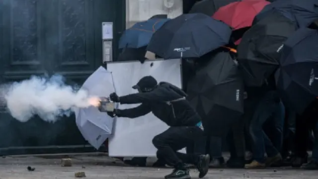 Seorang pengunjuk rasa menembakkan kembang api saat bentrok dengan polisi anti huru hara selama demonstrasi pada Hari Buruh Internasional, di Nantes, Prancis, pada Senin (1/5/2023). (Dok. AFP/Loic Venance)