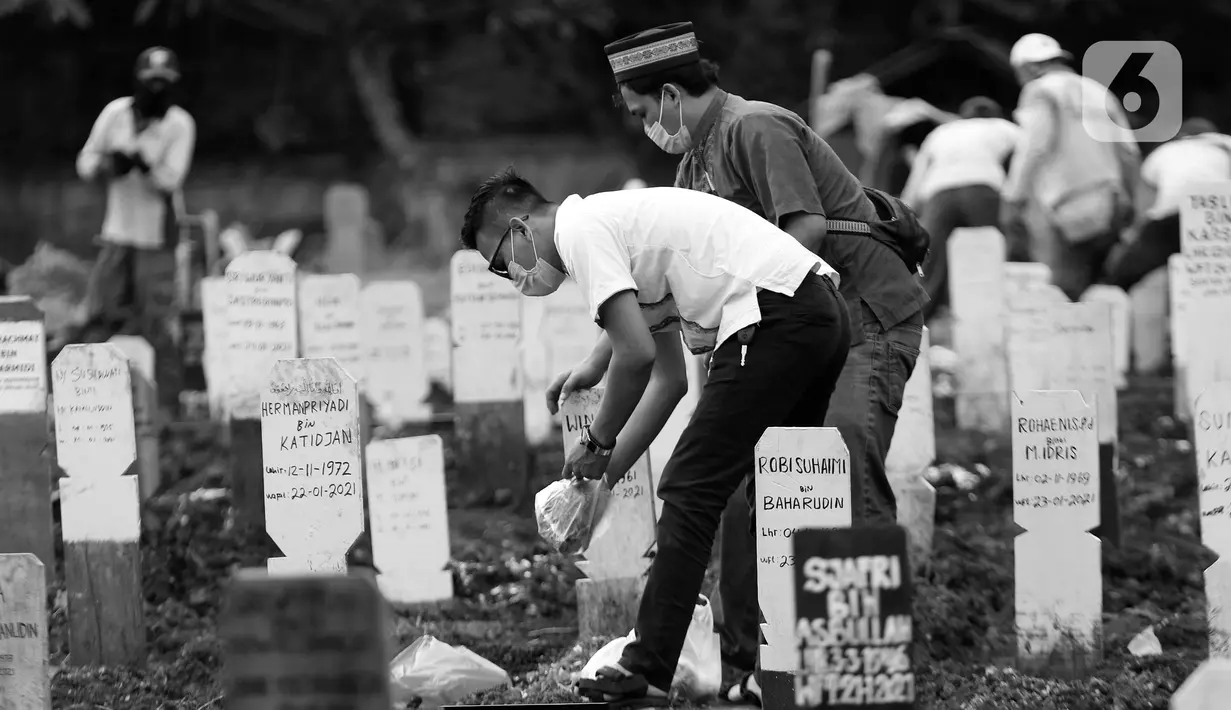 Anggota keluarga menabur bunga di makam kerabat yang dimakamkan dengan protokol COVID-19 di TPU Bambu Apus, Jakarta, Kamis (28/1/2021). TPU Bambu Apus merupakan satu dari enam lokasi pemakaman jenazah dengan protokol COVID-19 yang disediakan Pemprov DKI Jakarta. (Liputan6.com/Helmi Fithriansyah)