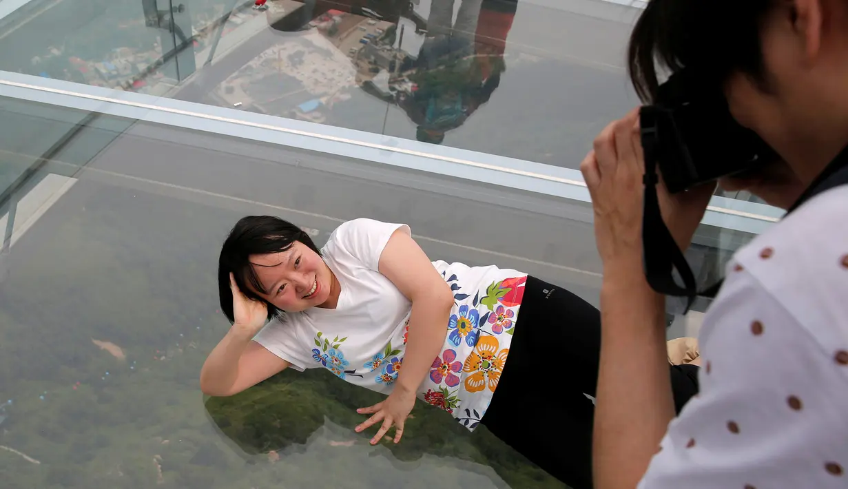 Seorang wanita berbaring saat difoto rekannya di atas platform kaca di Jurang Shilin, Beijing, Cina, (27/5). Platform ini luasnya mencapai 415 meter persegi. (REUTERS/Kim Kyung-Hoon)