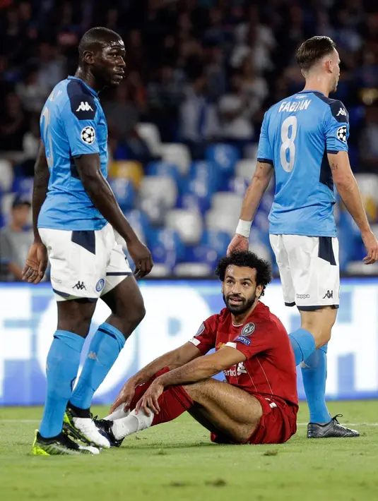 Penggawa Liverpool, Mohamed Salah duduk di atas lapangan melihat pemain Napoli, Kalidou Koulibaly pada matchday pertama Grup E Liga Champions di Stadion San Paolo, Selasa (17/9/2019). Juara bertahan Liverpool secara mengejutkan menyerah dua gol tanpa balas dari Napoli. (AP Photo/Gregorio Borgia)
