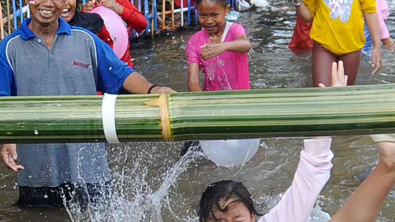 Lomba ini menggunakan batang pohon bambu yang membentang di atas kolam.
