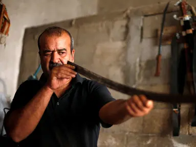 Pandai besi asal Palestina, Mueen Abu Wadi (45) memeriksa kelurusan pedang di bengkel kerjanya di Kota Gaza, Palestina (14/11). Mueen Abu Wadi meneruskan pekerjaan ayah dan kakeknya menjadi pembuat pedang. (REUTERS/Suhaib Salem)