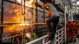 Pekerja mengelas besi penyangga saat proses pembongkaran papan reklame yang terpasang di JPO kawasan Salemba, Jakarta, Rabu (26/10) malam. Pembongkaran dilakukan lantaran  papan reklame itu diketahui tidak berizin. (Liputan6.com/Faizal Fanani)