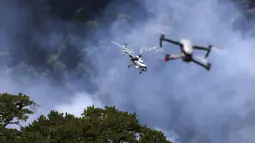 Sebuah helikopter berpartisipasi dalam operasi pemadaman kebakaran hutan di Koycegiz, Mugla, Turki, Senin (9/8/2021). Kebakaran hutan memaksa warga melarikan diri ke pantai untuk diselamatkan melalui laut. (AP Photo/Emre Tazegul)