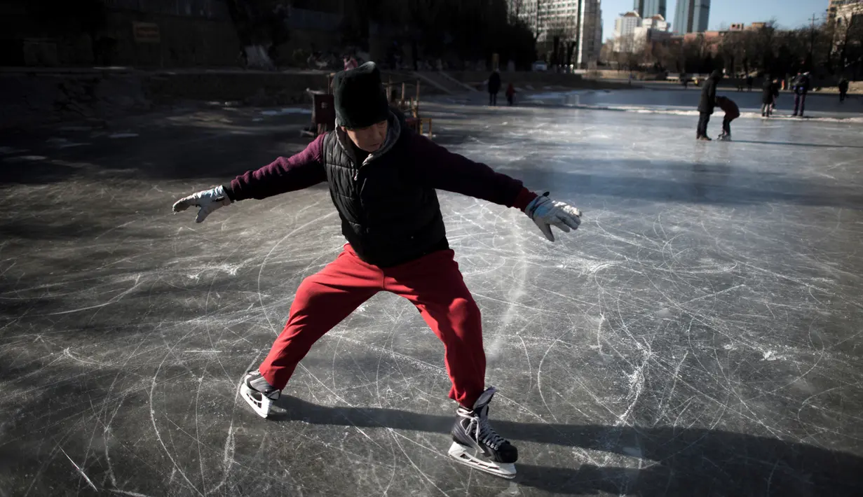 Aksi seorang warga saat bermain ice skating di sungai yang membeku di Beijing, China (21/1). Akibat membeku, Sungai ini menjadi objek wisata dadakan yang banyak diminati wisatawan. (AFP/Fred Dufour)