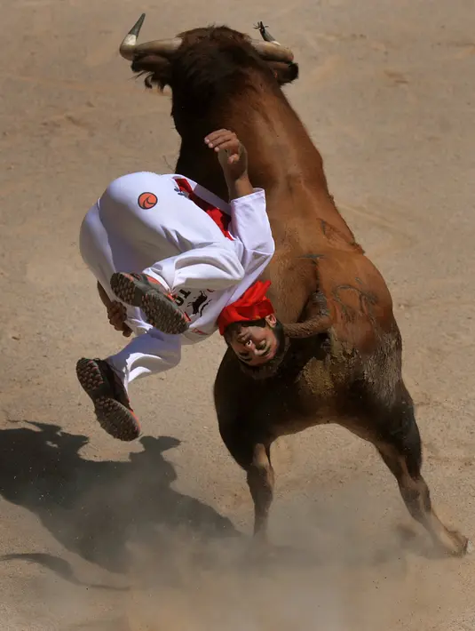 Seorang recortador melompati serudukan banteng selama Festival San Fermin di Pamplona, Spanyol, Sabtu (9/7). Aksi akrobatik melompati serangan banteng ini dinamakan recortadores. (REUTERS / Vincent West)