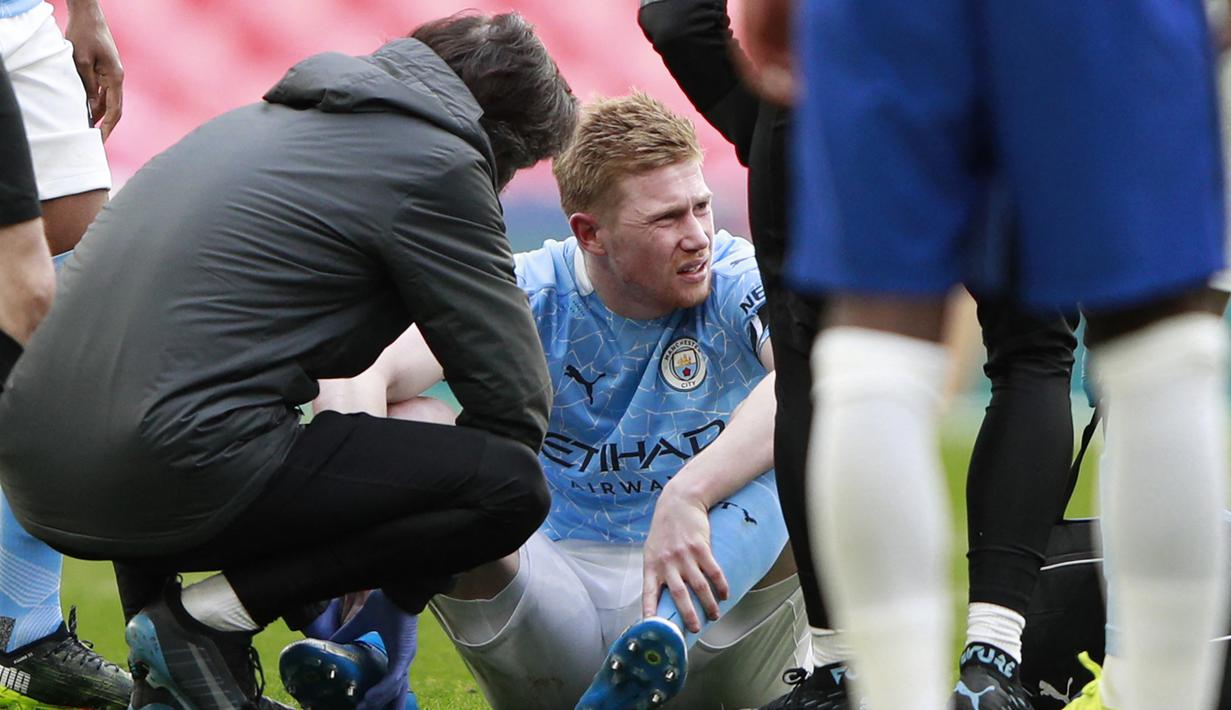 Gelandang Manchester City, Kevin De Bruyne mendapat perawatan dari tim medis usai mengalami cedera saat menghadapi Chelsea dalam laga semifinal Piala FA 2020/2021 di Wembley Stadium, London, Sabtu (17/4/2021). Manchester City kalah 0-1 dari Chelsea. (AFP/Ian Walton/Pool)