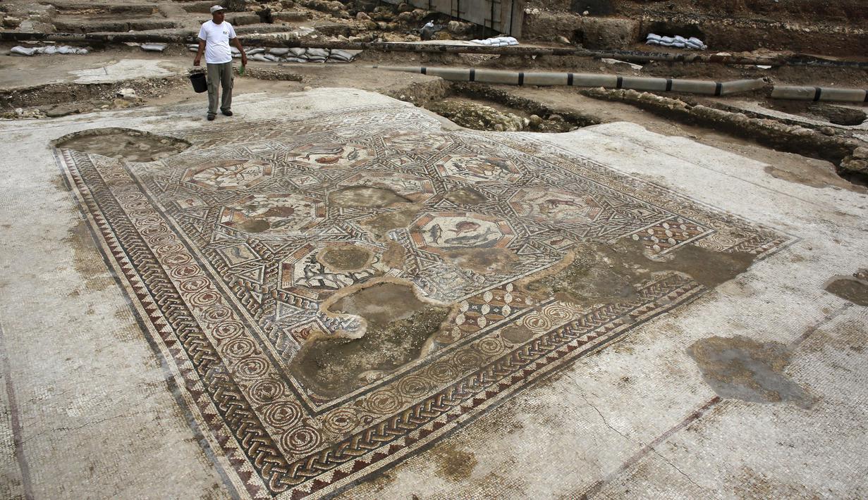 Seorang peneliti sejarah kuno saat ingin membersihkan lantai yang menampakkan gambar - gambar seperti  ikan dan binatang lainnya di Tel Aviv, Israel, Senin (16/11/2015). Tempat ini telah ada pada zaman Romawi dan periode Bizantium.  (REUTERS/Nir Elias)