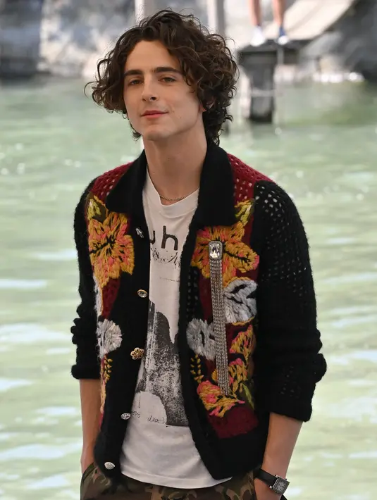 Aktor Prancis-AS, Timothee Chalamet saat tiba pada Venice Film Festival 2022 ke-79 di dermaga Hotel Excelsior di Lido, Venesia, Italia (2/9/2022). Ia tampil unik mengenakan kardigan rajutan bunga dan celana pendek camo besar. (AFP/Tiziana Fabi)