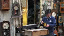 Hussein Mahmud (45) mengecek kerusakan jam antik di gudangnya di daerah Maidan Baghdad (20/2). Mahmud mengumpulkan jam kuno berumur 60 sampai 150  tahun lalu dari pelelangan dan penjual jalanan. (AFP Photo/Ahmad Al-Rubaye)