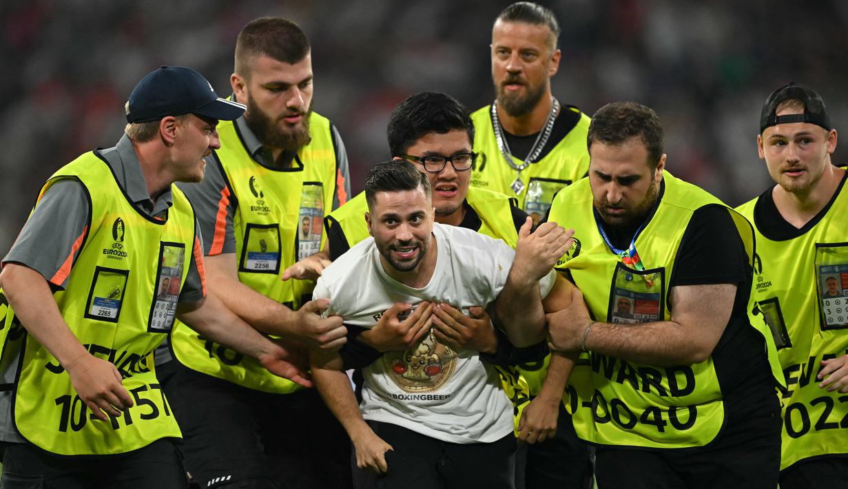 Segerombolan petugas keamanan, yang duduk di pinggir lapangan, kemudian berlari masuk lapangan untuk mengawal supporter itu pergi. (Fabrice COFFRINI / AFP)