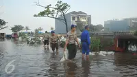 Petugas dibantu warga membetulkan  tanggul yang jebol di kawasan Perumahan Pantai Mutiara, Jakarta, Sabtu (4/6). Akibat tanggul jebol kawasan tersebut tergenang dengan ketinggian 50-60 sentimeter. (Liputan6.com/Gempur M Surya)