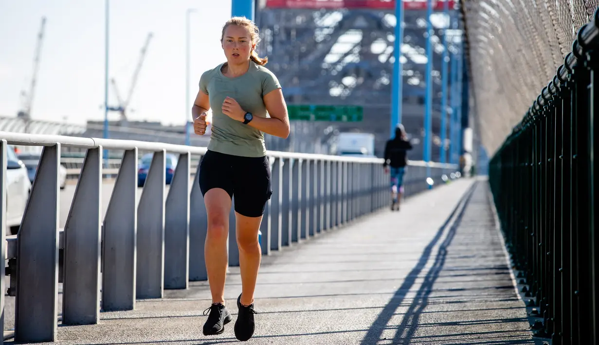 Seorang pelari berolahraga di Brisbane Story Bridge yang hampir sepi di Brisbane, Australia (30/6/2021).  Lockdown di Brisbane ini mulai berlaku pada Selasa malam. (AFP/Patrick Hamilton)