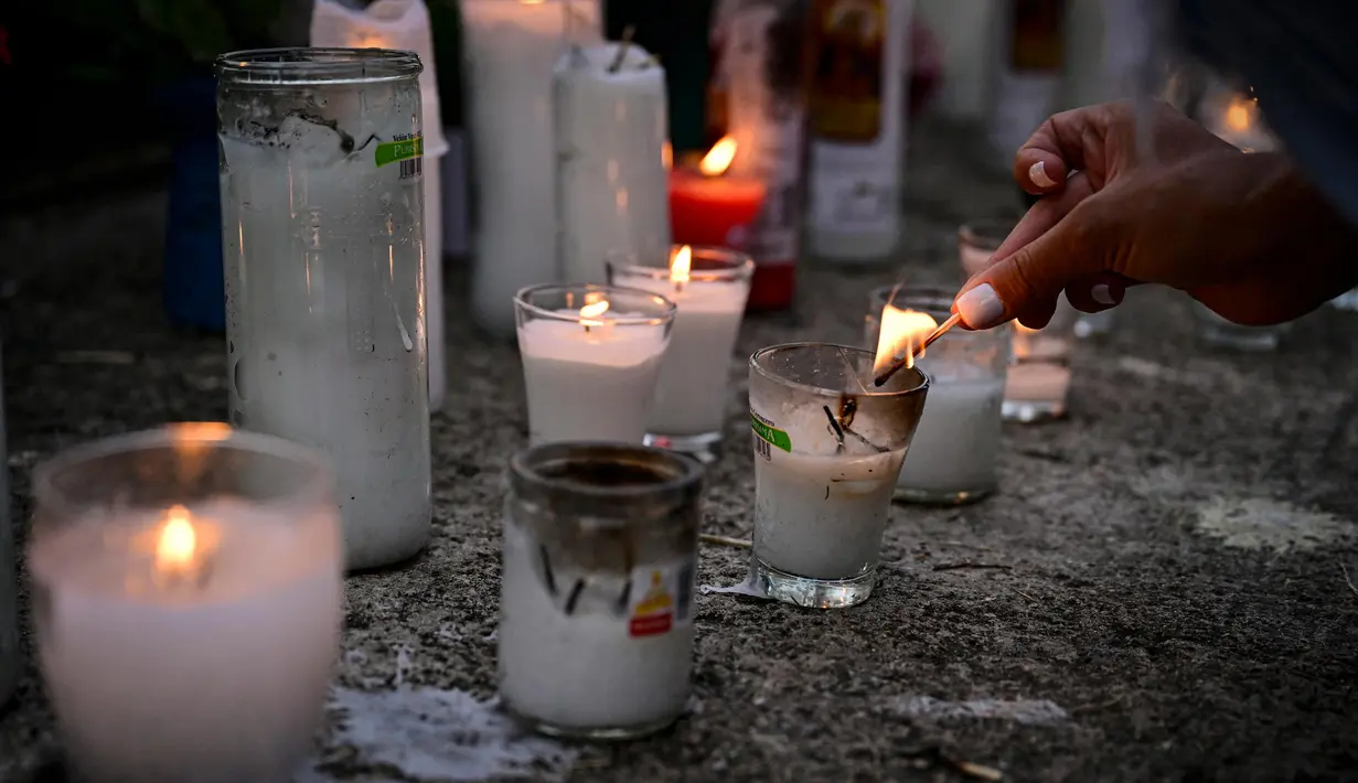 Seorang wanita menyalakan lilin untuk memberikan penghormatan kepada para korban tewas di depan klub malam Jet Set di Santo Domingo, Dominika pada 11 April 2025. (MARTIN BERNETTI/AFP)