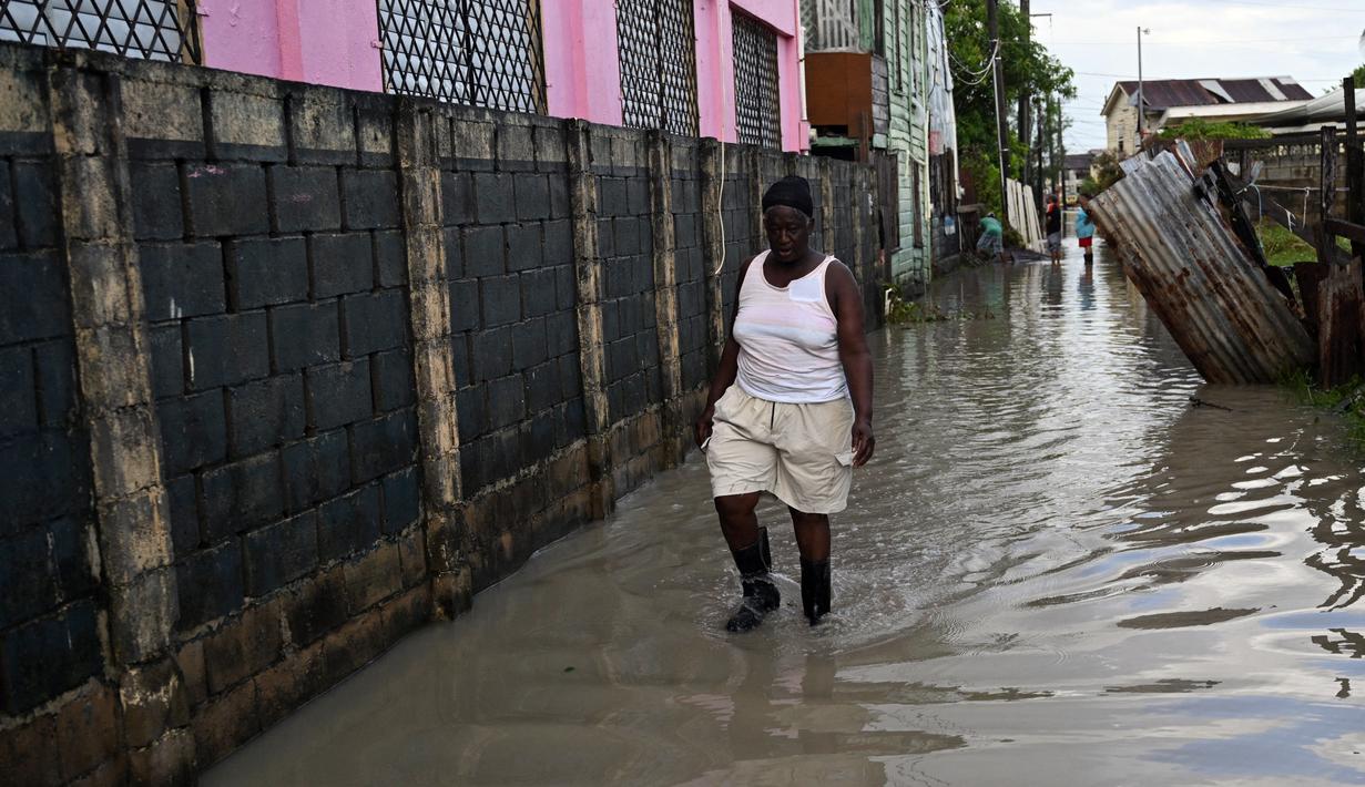 Seorang wanita berjalan melalui jalan yang banjir setelah Badai Lisa di Belize City, Belize, 3 November 2022. Badai Tropis Lisa menyebabkan banjir dan membuat sebagian negara itu menjadi gelap gulita. (Johan ORDONEZ/AFP)
