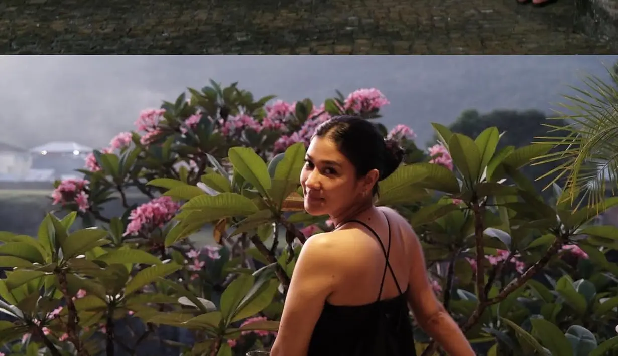 Berikutnya ia mengenakan jumpsuit hitam model backless cross neck. Dipadukan sandal hitam sambil membawa tas putihnya. Rambut panjangnya diikat cepol ke belakang. [@naymirdad]