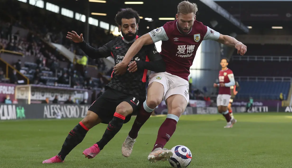 Penyerang Liverpool, Mohamed Salah berebut bola dan bek  Burnley, Charlie Taylor pada pekan ke-37 Liga Inggris di Stadion Turf Moor, Kamis (20/5/2021) dini hari WIB. Liverpool sukses menembus empat besar klasemen Liga Inggris setelah menang telak 3-0 atas Burnley. (Martin Rickett/Pool via AP)