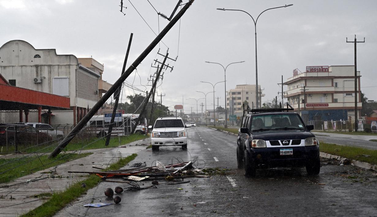 Kendaraan melewati jalan yang terhalang oleh cabang-cabang pohon setelah Badai Lisa di Ladyville, dekat Belize City, Belize, 3 November 2022. Badai Tropis Lisa menyebabkan banjir dan membuat sebagian negara itu menjadi gelap gulita. (Johan ORDONEZ/AFP)