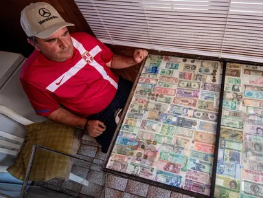 Pria Serbia, Zoran Milosevic dengan koleksi uang kertas dan koin dari seluruh dunia di rumahnya desa Pavlovci, Belgrade, 10 September 2018. Selama 36 tahun, pria yang bekerja sebagai tukang kunci itu mengumpulkan mata uang dunia. (AFP/ANDREJ ISAKOVIC)