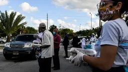 Relawan Asosiasi Komunitas Muslim Miami dan Yayasan Lumba-Lumba Miami mendistribusikan makanan buka puasa Ramadhan di Miami Gardens, Florida, Amerika Serikat, Selasa (27/4/2021). Distribusi makanan dilakukan secara drive thru. (CHANDAN KHANNA/AFP)