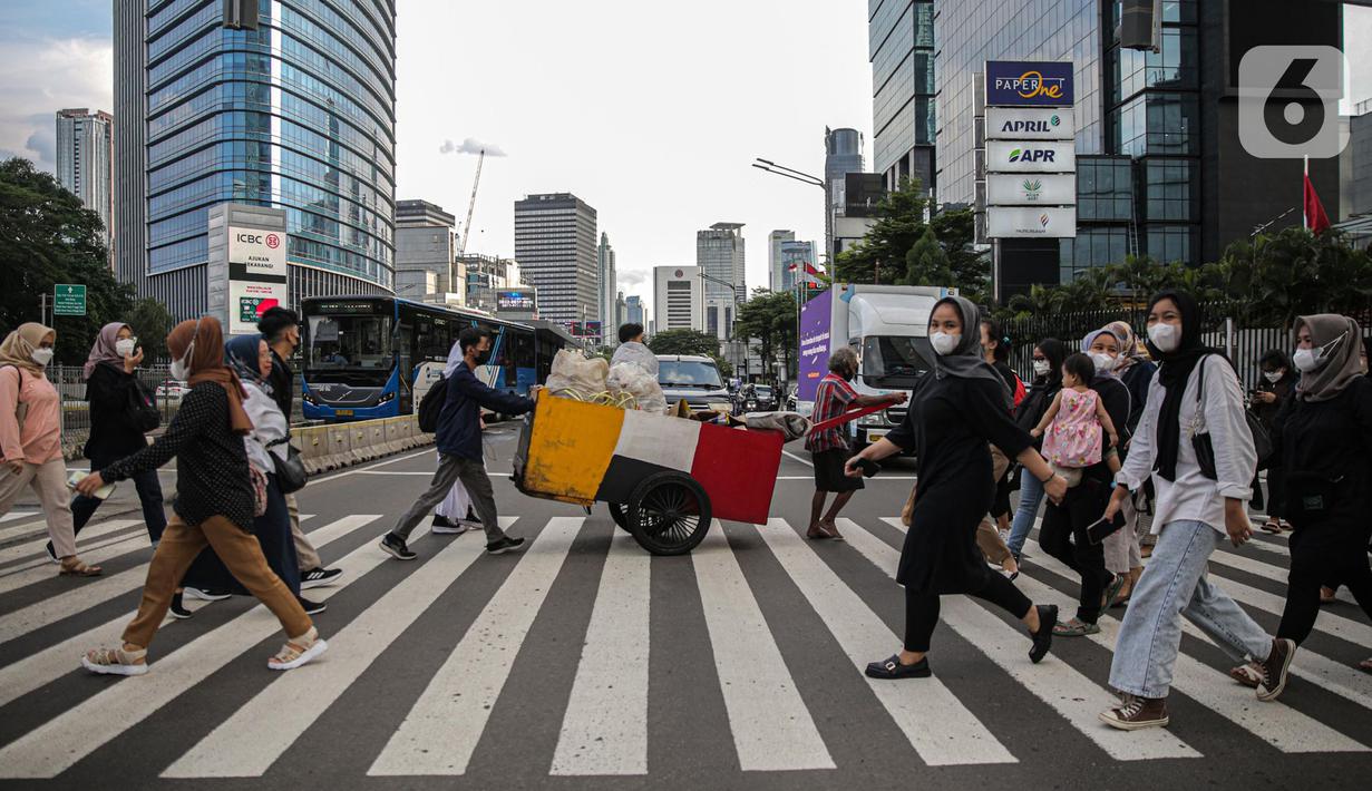 Pekerja kantoran melintas di pelican cross kawasan Jalan Thamrin, Jakarta, Kamis (5/1/2023). Pencabutan Pemberlakuan Pembatasan Kegiatan Masyarakat (PPKM) dinilai untuk menggenjot ekonomi Indonesia 2023 yang diproyeksi suram akibat resesi global. (Liputan6.com/Faizal Fanani)