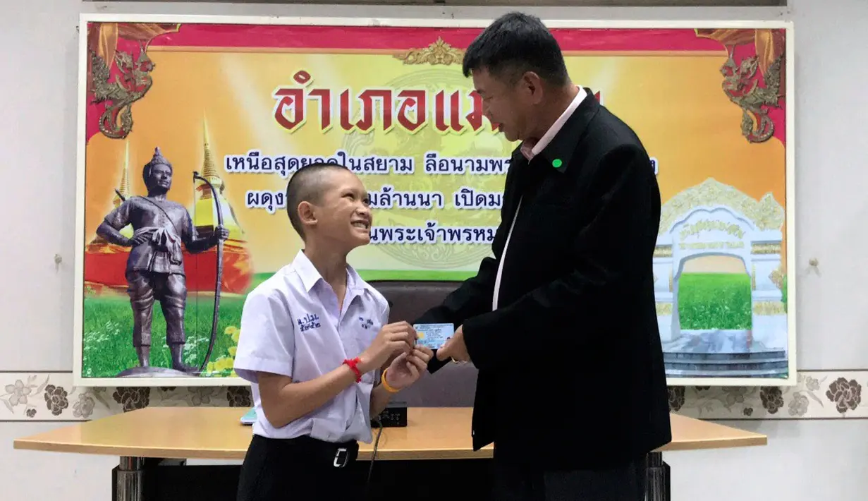 Salah seorang remaja, Mongkol Boonpiam menerima kartu identitas sebagai warga negara Thailand di distrik Mae Sai, Rabu (8/8). Korban gua Thailand tersebut selama ini hidup tanpa memiliki status kewarganegaraan (Chiang Rai Public Relations Office via AP)