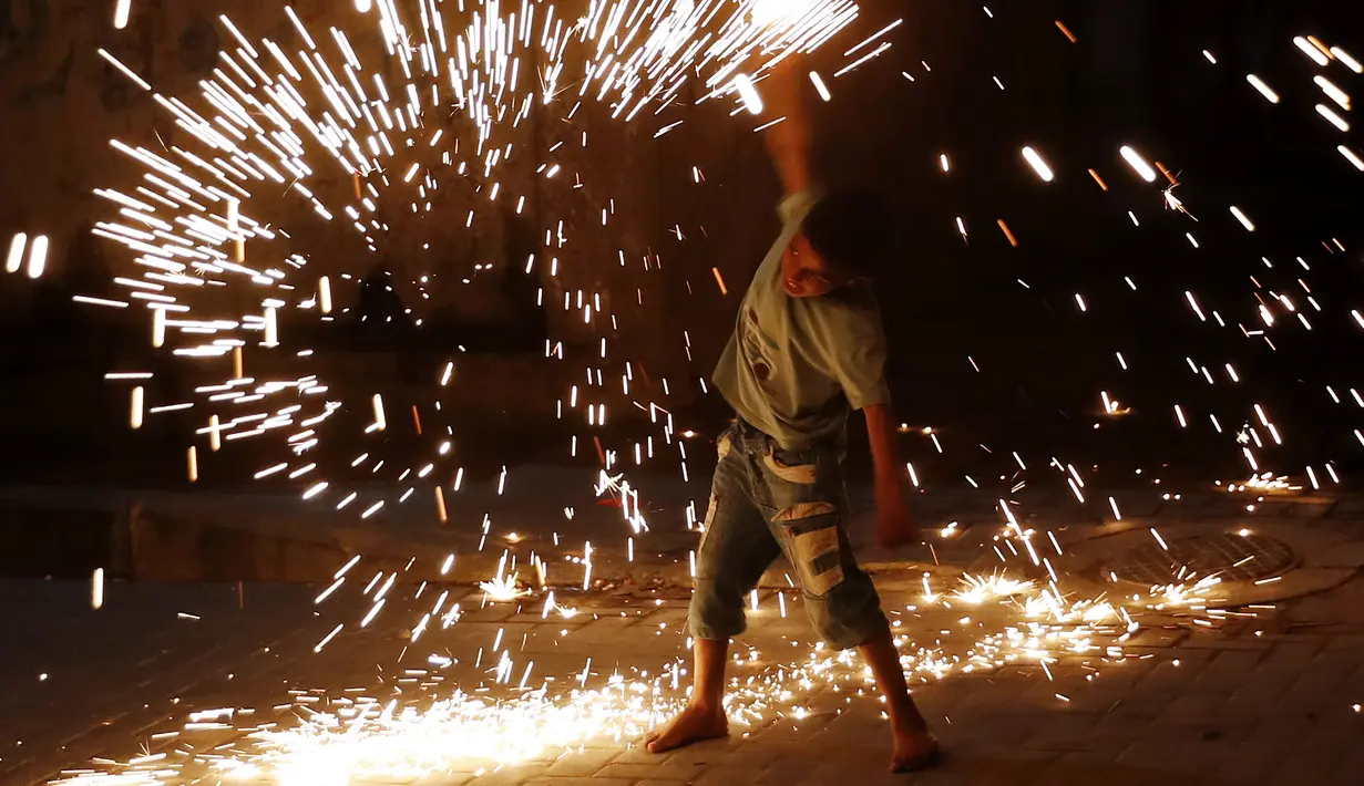 Seorang anak laki-laki bermain kembang api saat merayakan puasa bulan suci Ramadhan di sepanjang gang di Kota Gaza, Palestina, Selasa (20/4/2021). Umat muslim dunia melangsungkan puasa selama satu bulan penuh pada bulan suci Ramadhan. (AP Photo/Adel Hana)