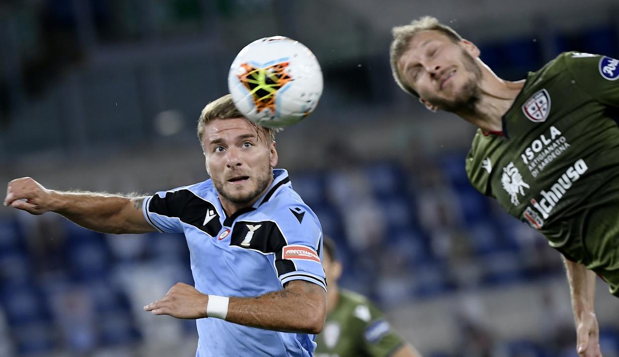 Penyerang Lazio, Ciro Immobile, berebut bola dengan bek Cagliari, Ragnar Klavan, pada laga lanjutan Serie A pekan ke-35 di Stadio Olimpico, Jumat (24/7/2020) dini hari WIB. Lazio menang 2-1 atas Cagliari.(AFP/Filippo Monteforte)